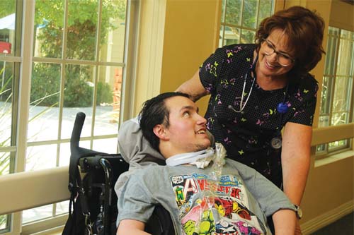 Boy in wheelchair smiling at staff member